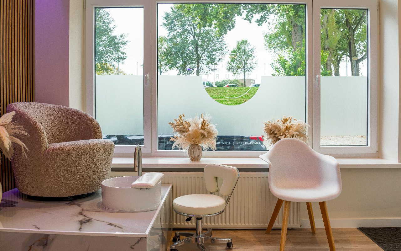 Zithoek bij het raam met fauteuil en voetenbak